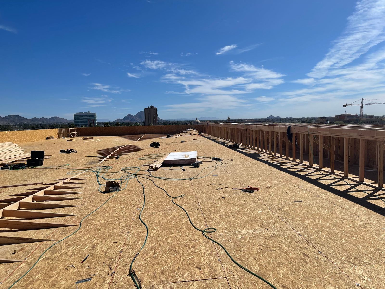 Acacia Heights Phase II rooftop: sheathed roof deck and parapet framing with Camelback Mountain beyond