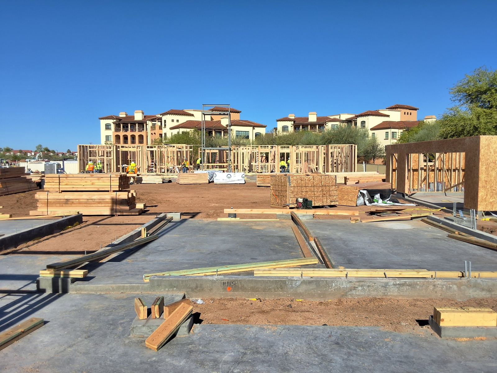 Maravilla Scottsdale: crews raising first-floor wall framing beside lumber packages
